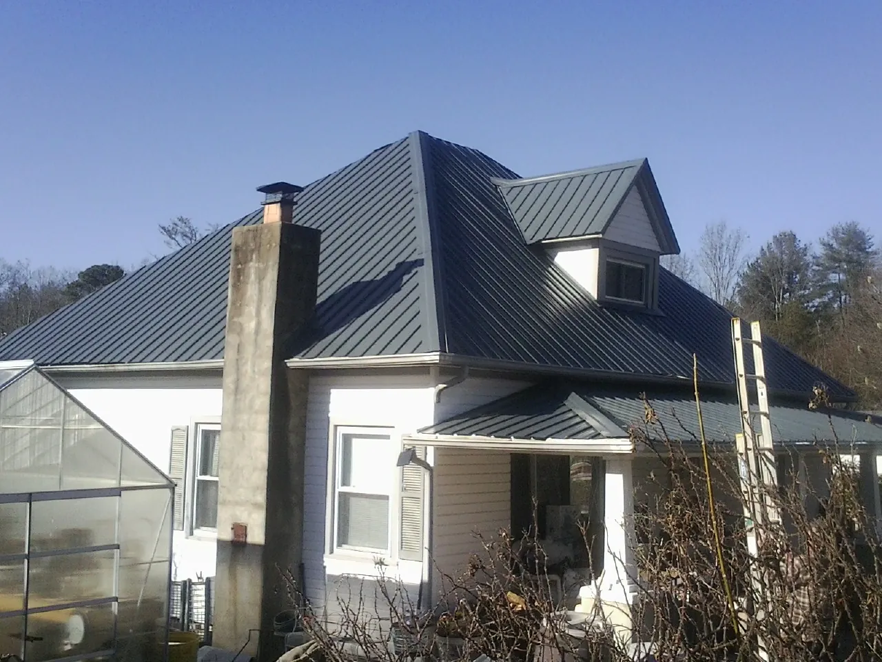 Dark blue standing seam metal roof on a white farmhouse with dormer — Slate & Tile Roof Repair by Roofing Brothers in New Rochelle