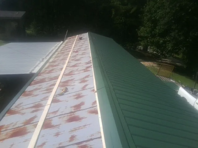 Old rusted panels beside newly installed green metal roofing — Wind Damage Roof Repair by Roofing Brothers in New Rochelle
