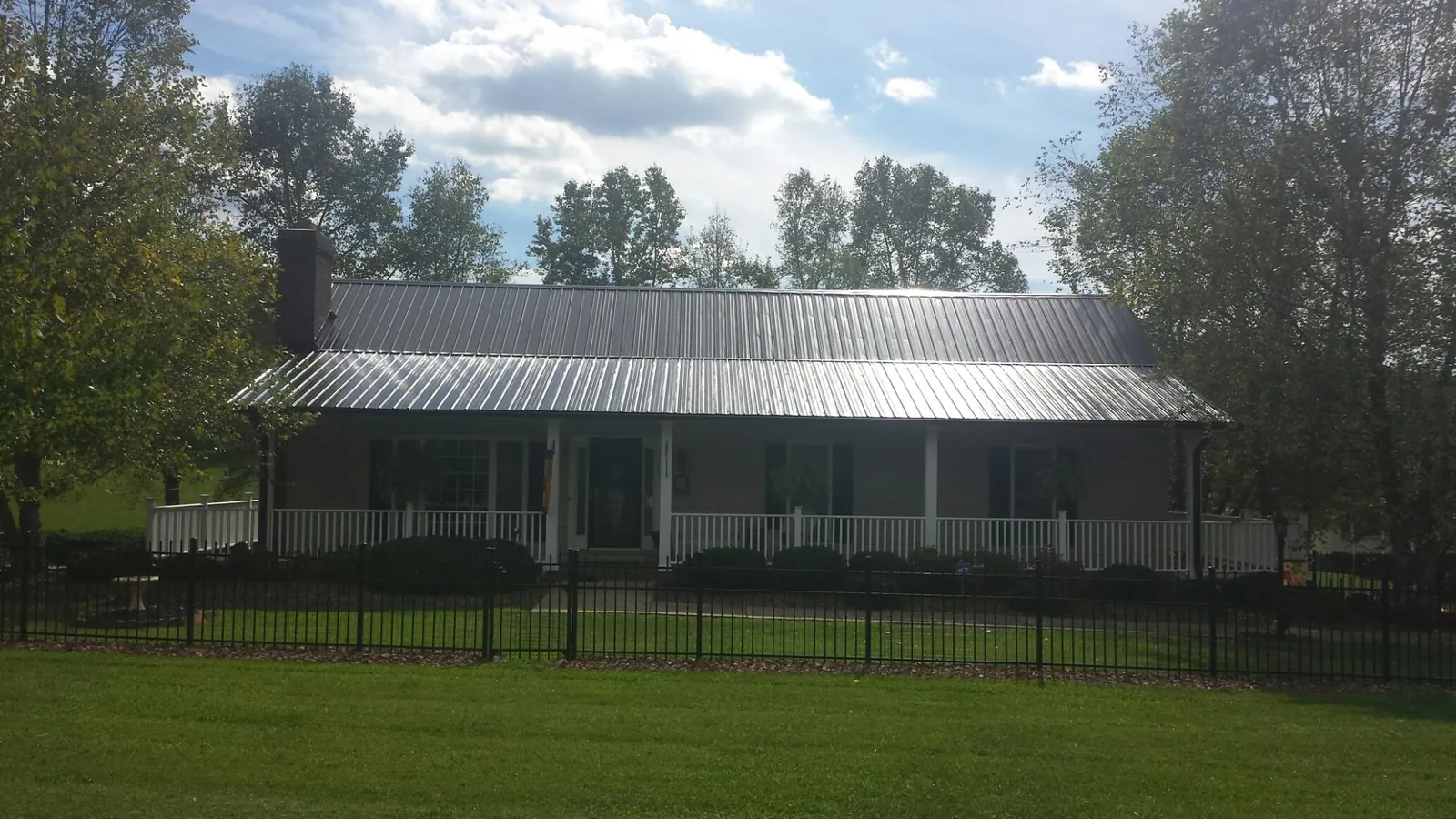 Gray metal roof on a brick ranch with a full width front porch — Gutter Guard Installation work by our crew in New Rochelle