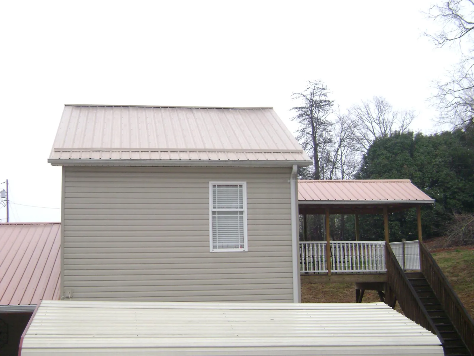 Tan metal roofs on a two story addition and attached porch, from a Roof Replacement job in New Rochelle