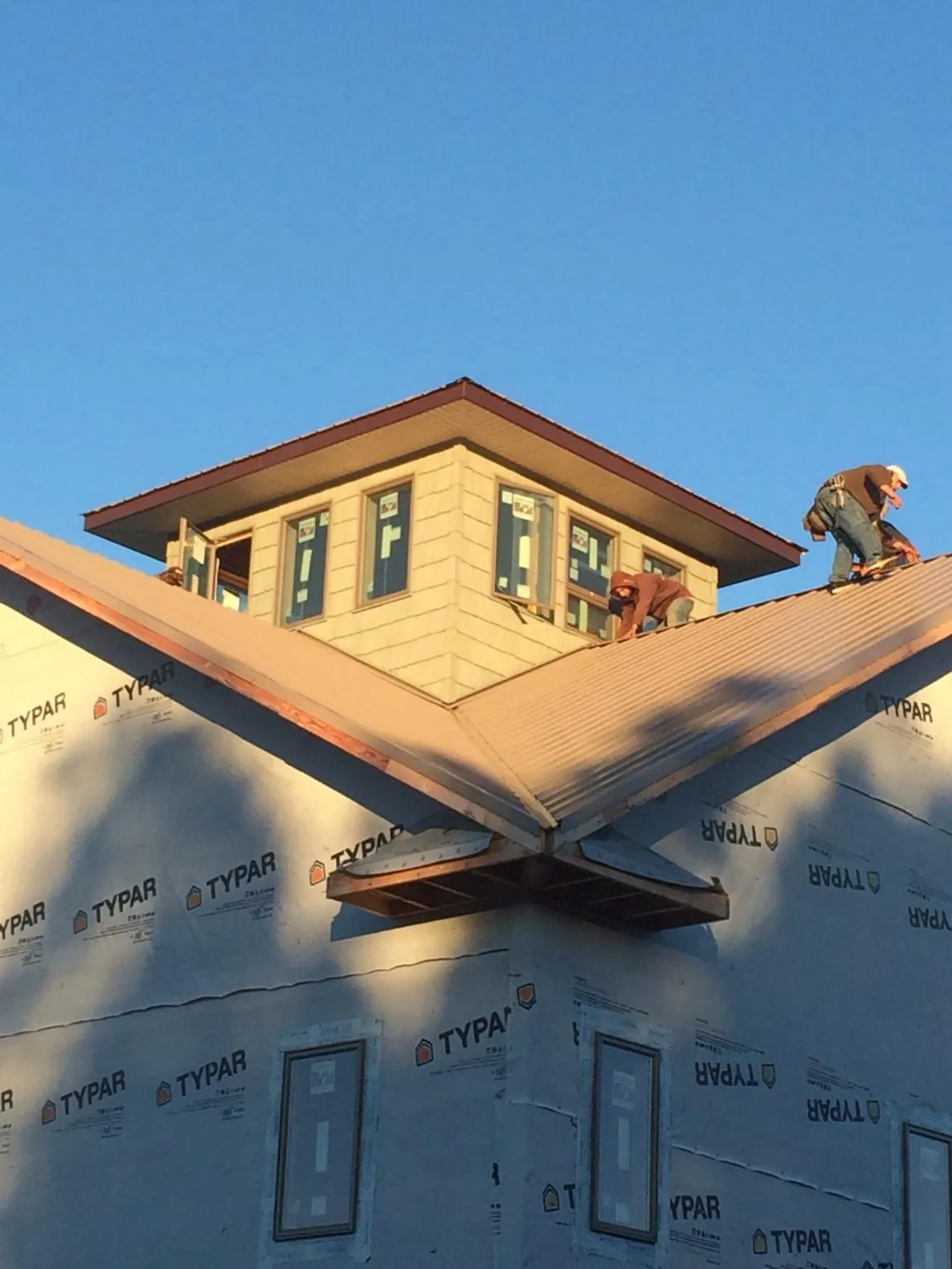 Roofers working around a rooftop cupola on a new metal roof at sunset — Roof Waterproofing in New Rochelle by Roofing Brothers
